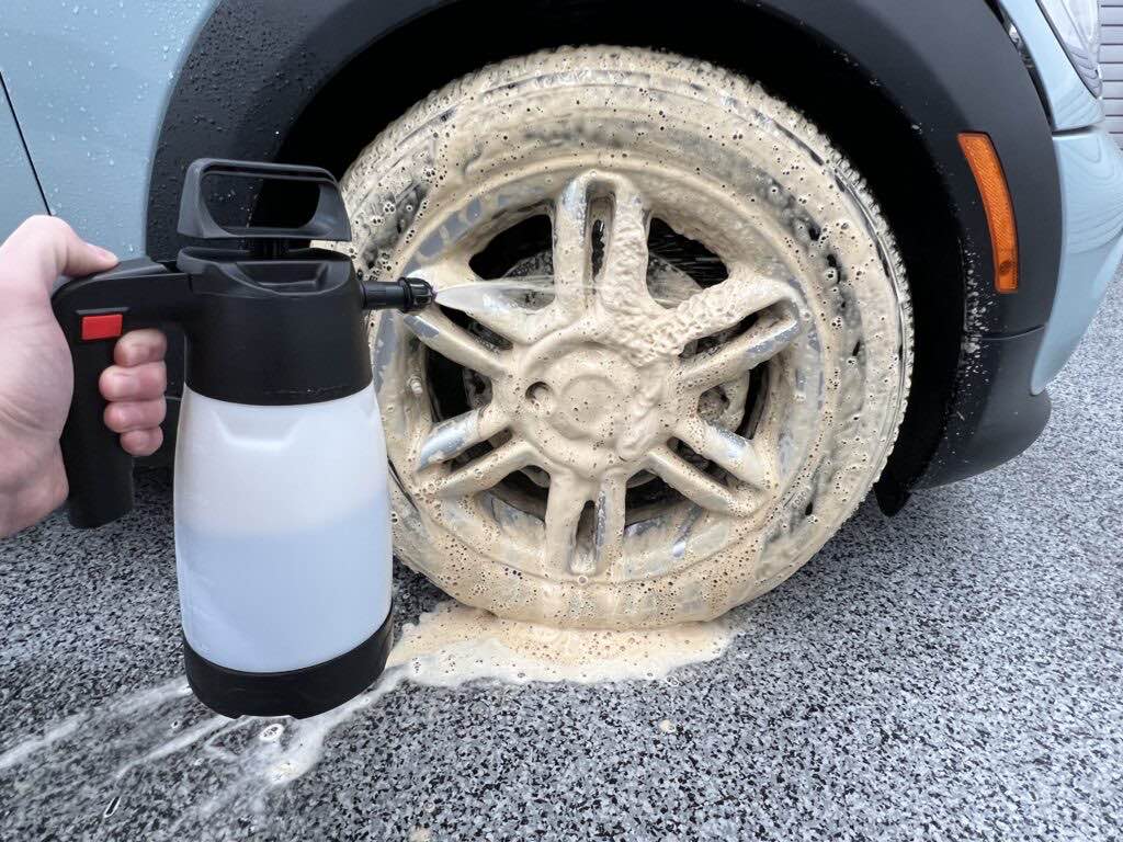 Dark Fury at 10:1 foaming over a silver alloy wheel and tire on a grey car, applied with a hand pump sprayer