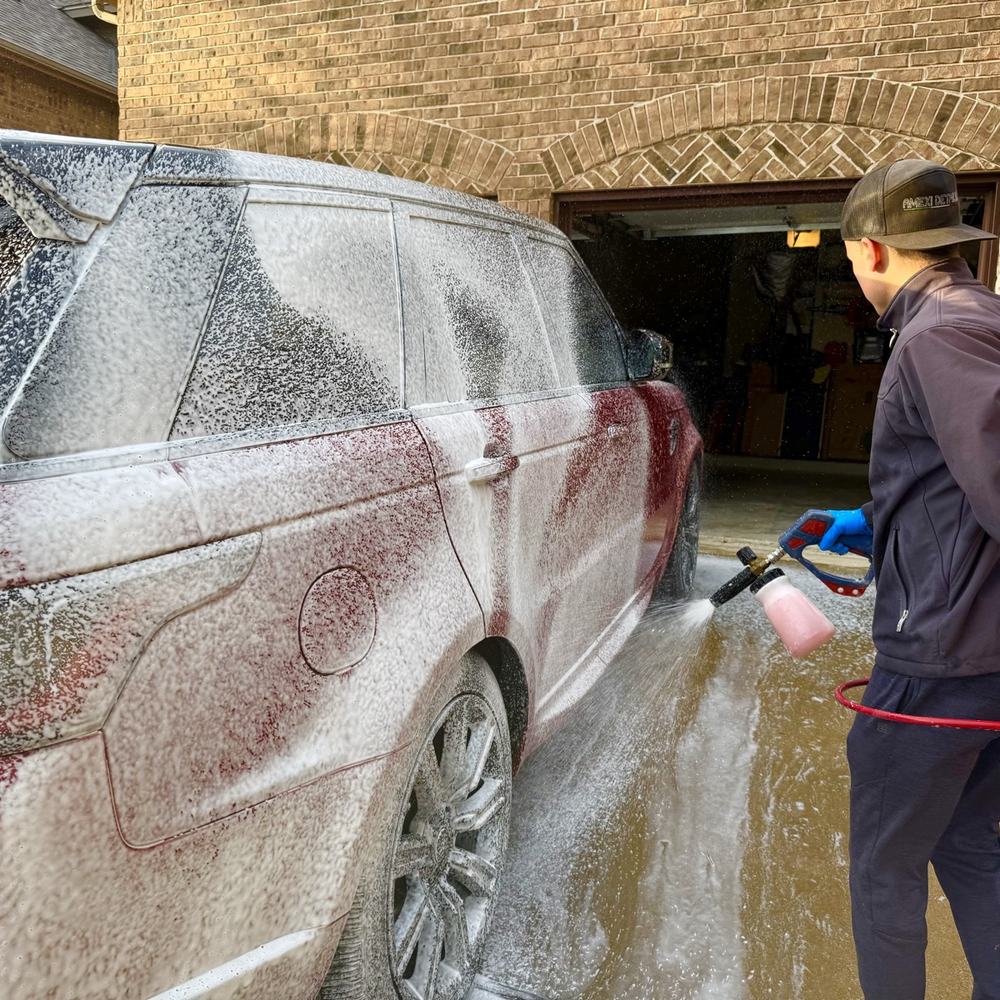 Detailer rinsing a red Range Rover